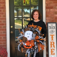 Handmade Halloween mummy wreath held by designer of Wisp and Wonder Designs