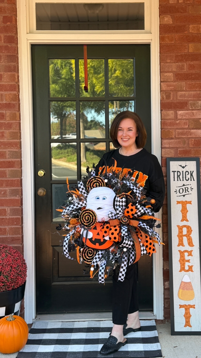 Handmade Halloween mummy wreath held by designer of Wisp and Wonder Designs