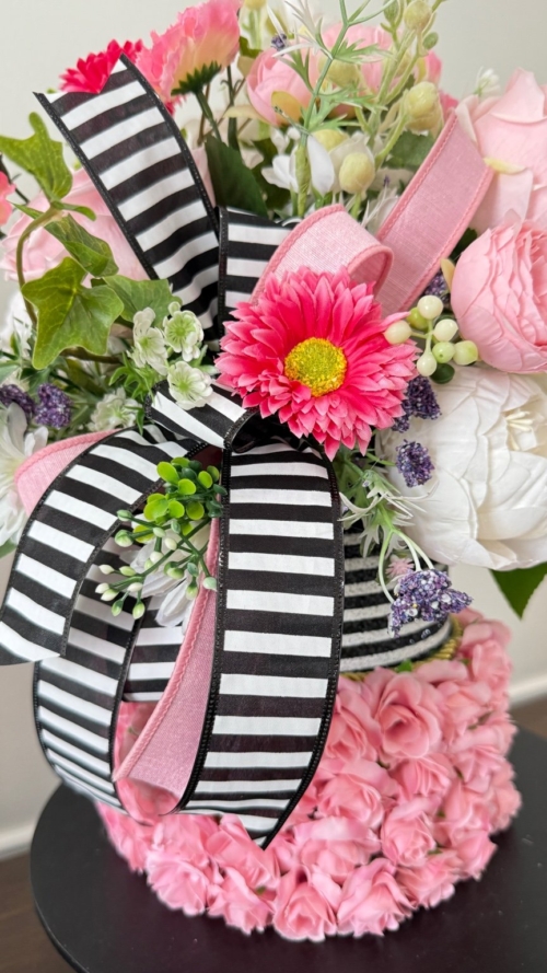 Detail of black striped ribbon and layered pink flowers in faux cake centerpiece