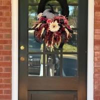 Handcrafted moody bohemian harlequin pumpkin wreath with black moss base and boho ribbon.