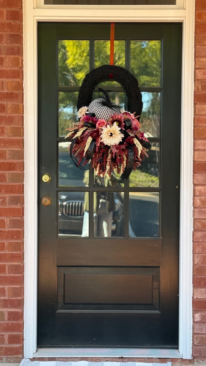 Handcrafted moody bohemian harlequin pumpkin wreath with black moss base and boho ribbon.
