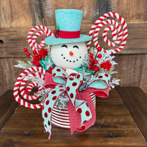 Full display of handmade snowman candy cane centerpiece on a wooden table.