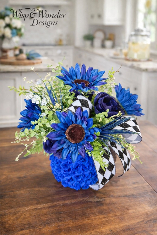 Styled tabletop using cobalt blue stacked design with sunflowers and greenery.