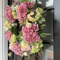 Side view of full spring floral wreath with pink hydrangeas pastel roses, and layered greenery