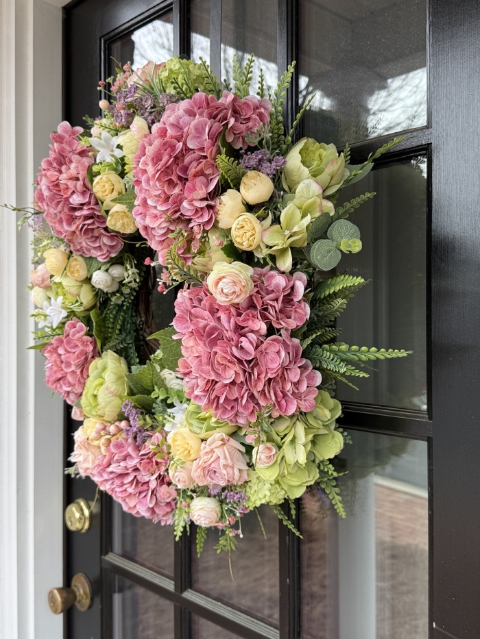Side view of full spring floral wreath with pink hydrangeas pastel roses, and layered greenery