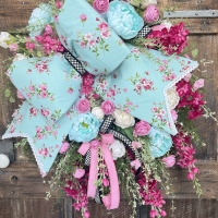 Full design of handmade spring floral wreath with aqua bow and vibrant pink flowers