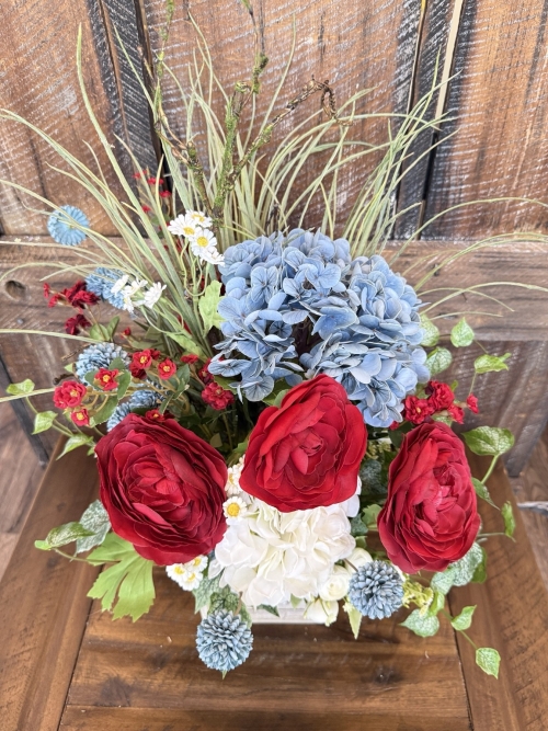 summer floral centerpiece with red blooms, blue flowers, white florals and greenery