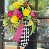 Pink, lime green and yellow mini wreath displayed on a black door