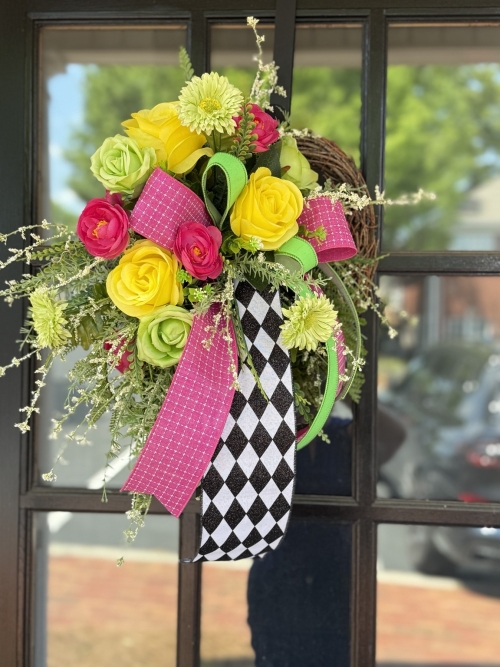 Pink, lime green and yellow mini wreath displayed on a black door