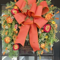 Luxury orange peony grapevine wreath on black front door with designer ribbon and vibrant peonies