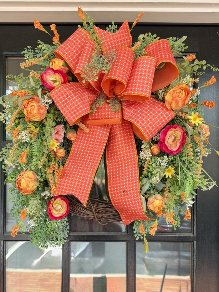 Luxury orange peony grapevine wreath on black front door with designer ribbon and vibrant peonies