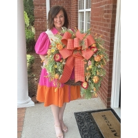 Designer holding luxury orange peony grapevine wreath with designer ribbon and bright florals
