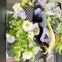 Side view of luxury bee wreath with Gerber daisies and lavender peonies