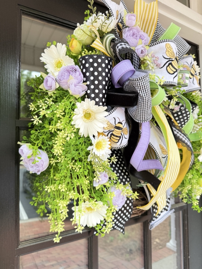 Side view of luxury bee wreath with Gerber daisies and lavender peonies