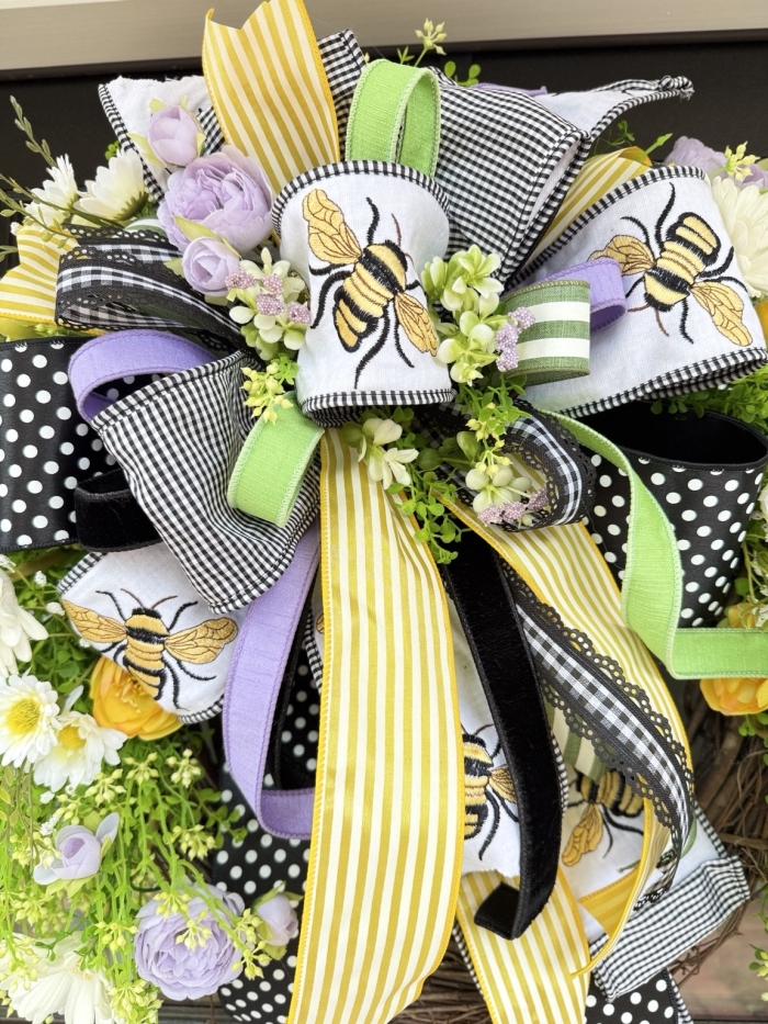 Close up of luxury bow featuring designer ribbons in polka dot, embroidered bee, velvet and satin