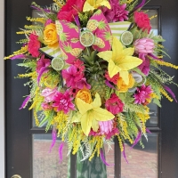 pineapple summer wreath displayed on black front door with vibrant pink yellow and green florals