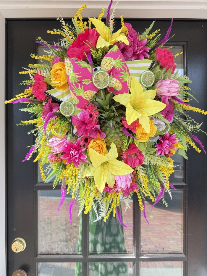 pineapple summer wreath displayed on black front door with vibrant pink yellow and green florals