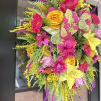 angled view of bright pineapple summer wreath with layered greenery and bold floral design