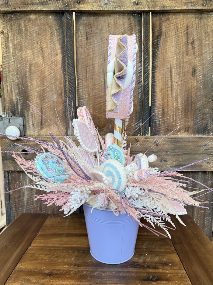 Side view of a handcrafted candy-themed centerpiece featuring glitter candy decorations, pastel lollipops, and sparkling lavender accents.
