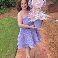 Designer holding a pastel candy party centerpiece with oversized candy decorations, glitter accents, and whimsical sweet shop details.