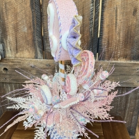 Pastel candy party centerpiece with faux candy swirls, sprinkle-covered sweets, glitter sprays, and frosted pink foliage viewed from the side.