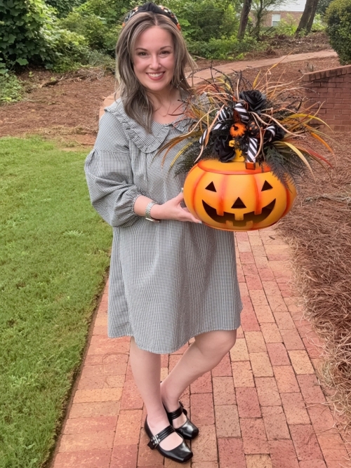 Woman holding a Jack O Lantern Halloween centerpiece showing the scale of the handcrafted pumpkin arrangement.