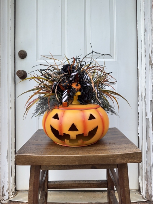 Orange Jack O Lantern Halloween centerpiece with removable floral top, black roses, and black and white ribbon.